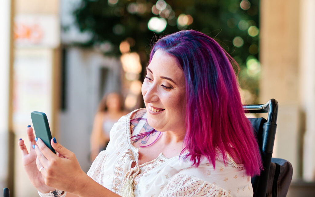 A woman with disabilities in a wheelchair using smartphone to scroll the screen