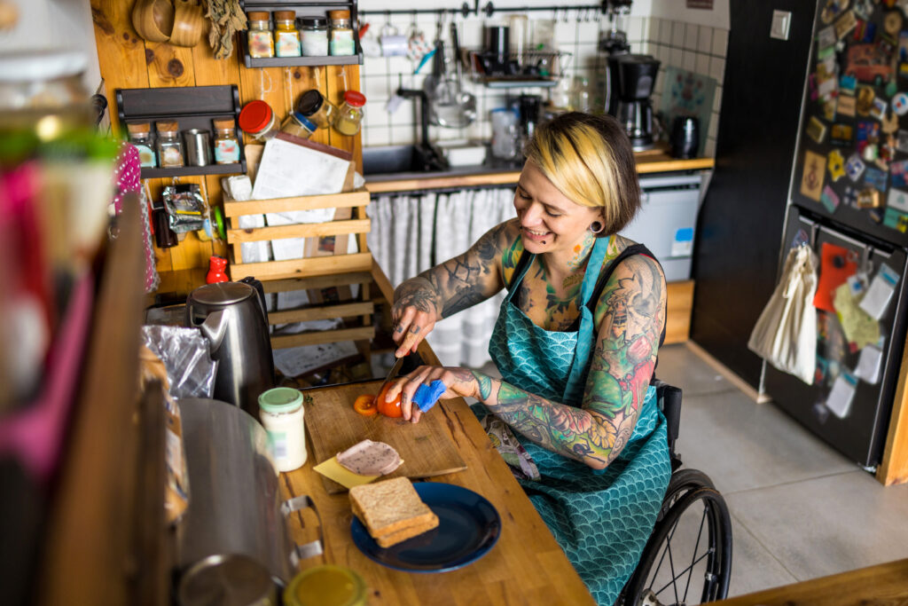 Woman in wheelchair preparing food in kitchen at home